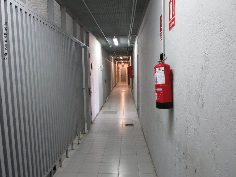 Pasillo largo con rejas a un lado y extintor al otro de primera acogida en Motril