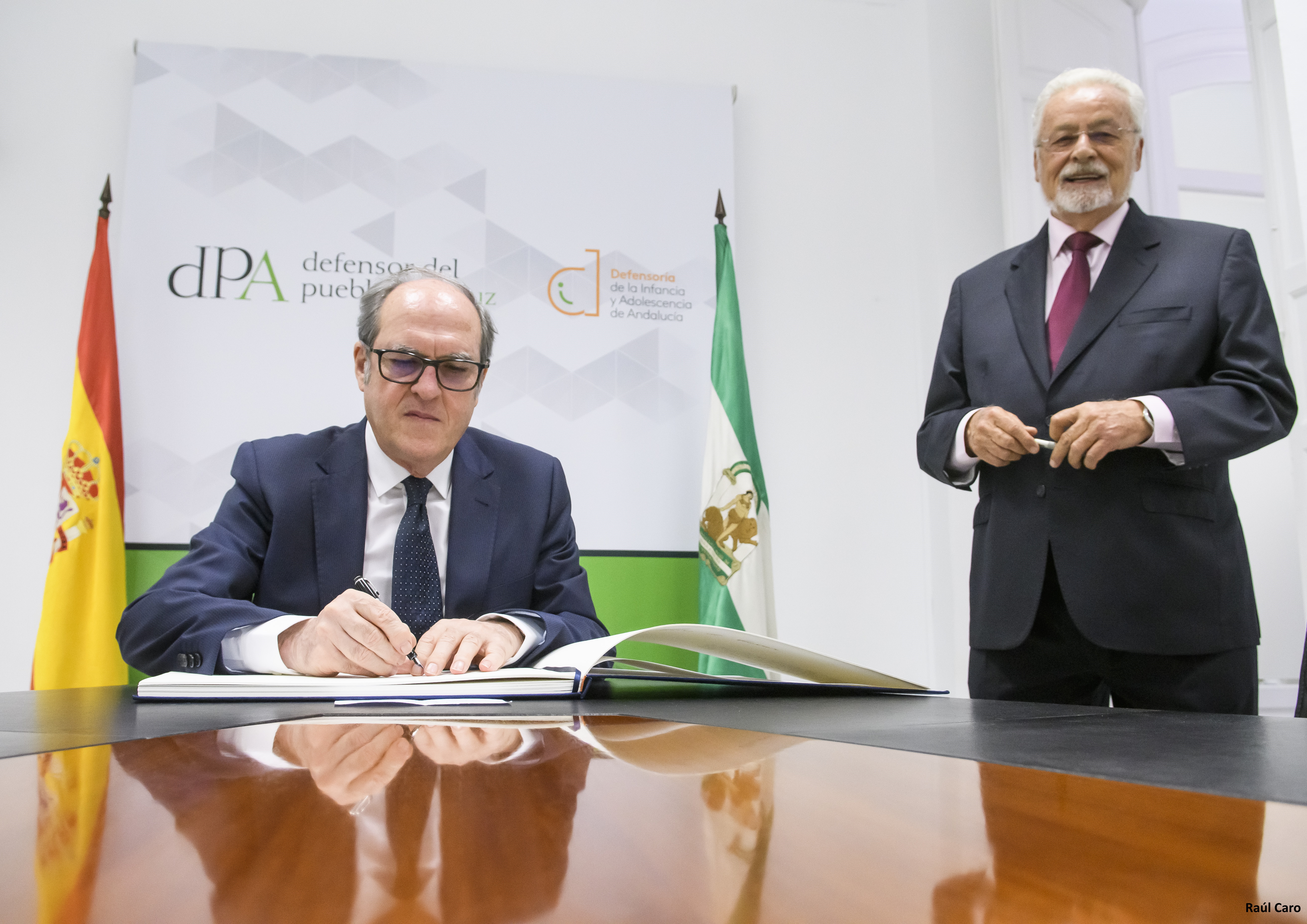 El Defensor del Pueblo firma ante la atenta mirada del Defensor del Pueblo Andaluz
